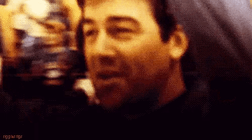 a close up of a man 's face with a blurry background and the words rigg 's wings on the bottom