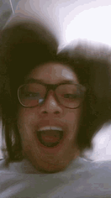 a woman wearing glasses is making a funny face with her mouth open
