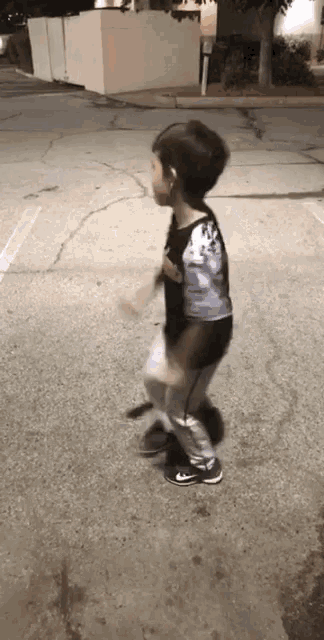 a young boy in a black shirt is walking down a street .