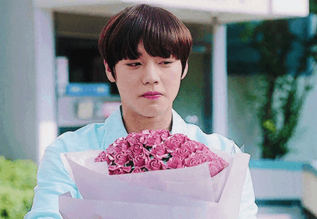 a man is holding a bouquet of pink roses in front of a building