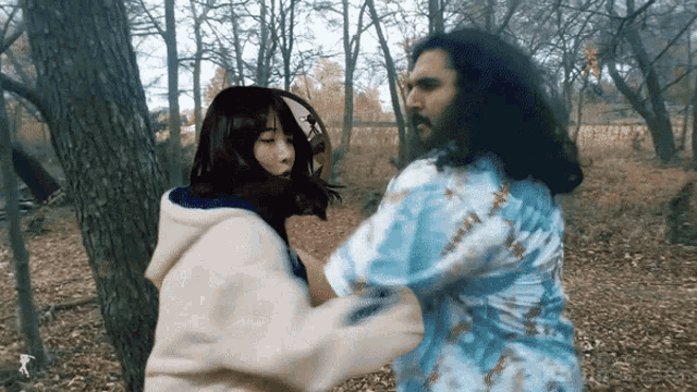 a man and a woman are fighting in the woods and the man has a beard