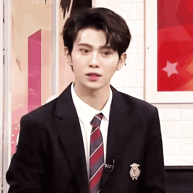 a young man in a suit and tie with a brooch that says ' the top ' on it