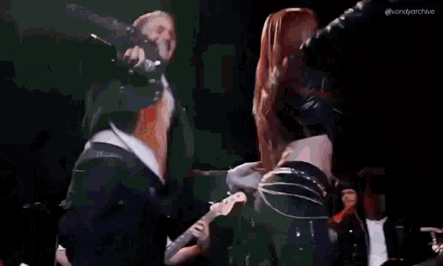 a man is playing a guitar while a woman is dancing on a stage .