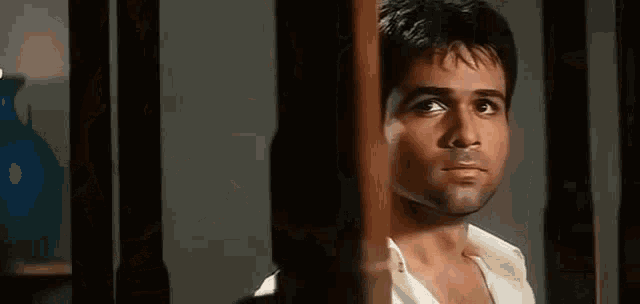 a man in a white shirt is looking out a window .
