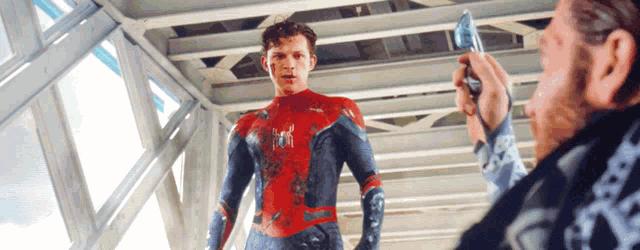 a man is taking a picture of a man in a spiderman costume