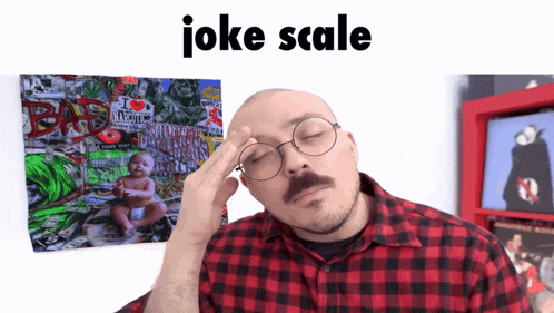 a man wearing glasses and a plaid shirt holds his hand to his head in front of a poster that says joke scale