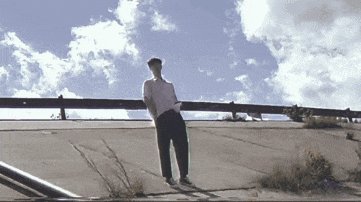 a man in a white shirt and black pants is standing on a sidewalk