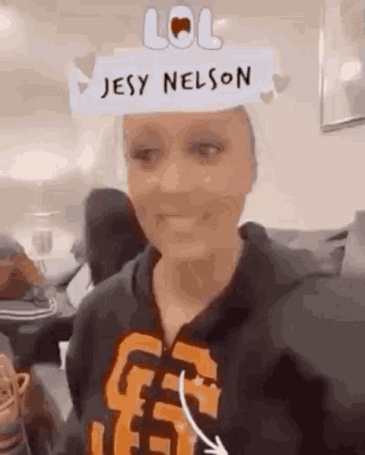 a woman wearing a hoodie with the name jesy nelson on it is sitting in a living room .