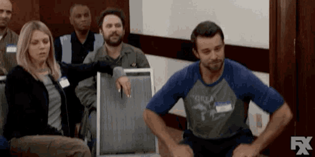 a group of people are sitting in chairs in a room and a man is sitting on a chair .
