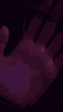 a close up of a person 's hand with a purple background