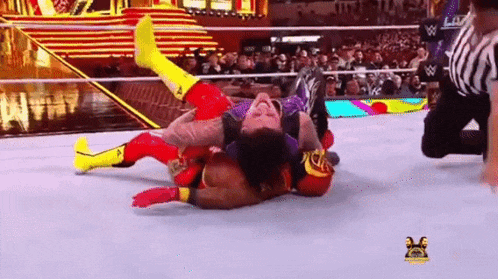 two wrestlers are wrestling in a wrestling ring with a referee watching .