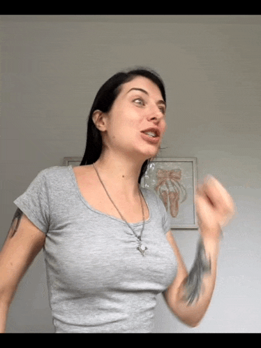 a woman with a tattoo on her arm is wearing a grey t-shirt