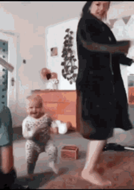 a woman and a baby are dancing in a living room