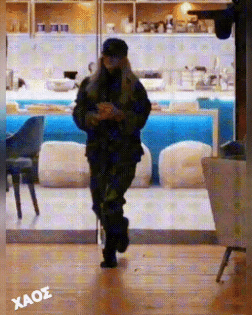 a woman walking in a room with the word xaos written on the bottom