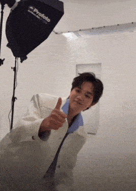 a young man giving a thumbs up in front of a profoto light