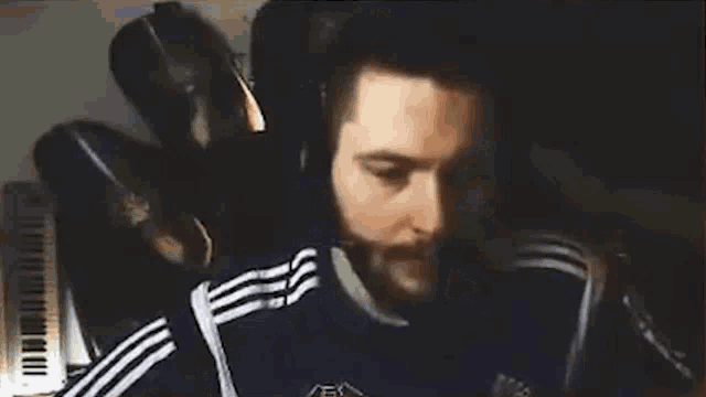 a man with a beard is standing in front of a piano .