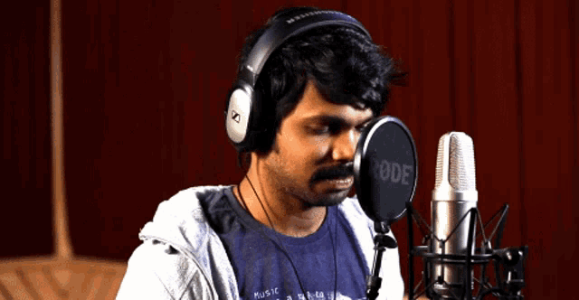 a man is singing into a rode microphone while wearing headphones
