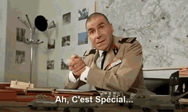 a man in a military uniform is sitting at a desk with a toy airplane on it .