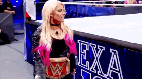 a woman is standing in a wrestling ring wearing a wrestling belt and a choker .