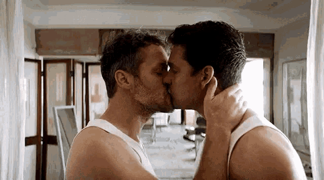 two men are kissing each other in front of a mirror .