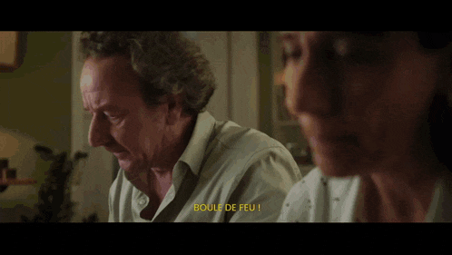 a man and woman are sitting at a table and the word boule is on the screen