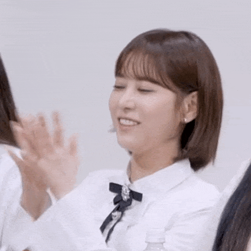 a woman in a white shirt is clapping her hands in front of a group of girls .