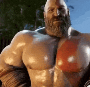 a man with a beard and huge muscles is standing in front of a tree .
