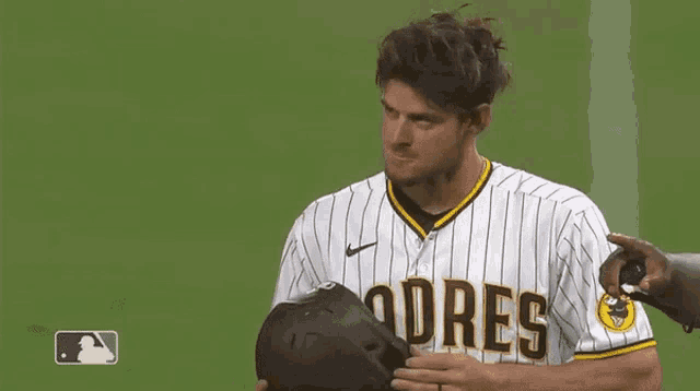 a padres baseball player is adjusting his helmet on the field
