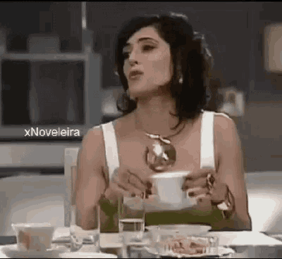 a woman is sitting at a table with a cup of coffee in her hand .