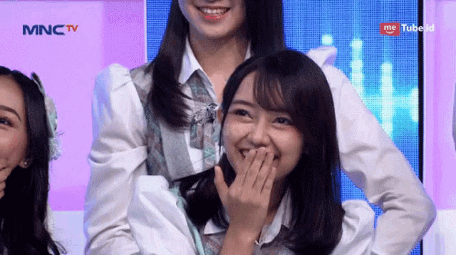 a group of women are standing in front of a mnctv screen