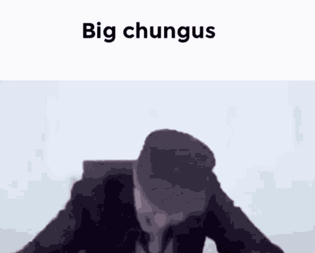 a man in a suit is sitting at a desk with his head in his hands and the words `` big chungus '' above him .