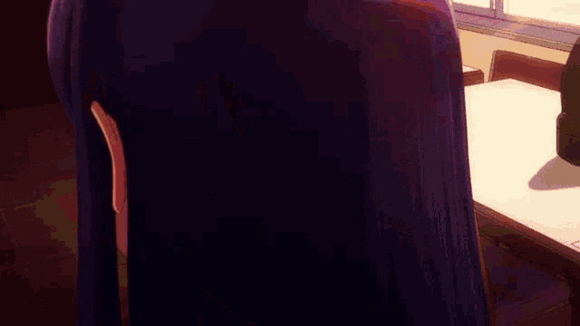 a girl with long purple hair is sitting at a table in a restaurant .