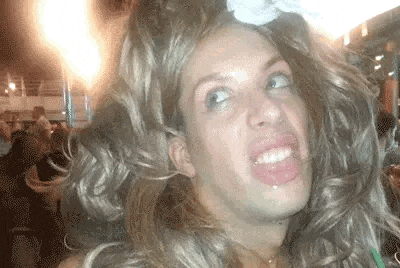 a man is wearing a wig and making a funny face at a party .