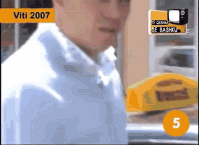 a man in a blue shirt is standing in front of a taxi cab with the number 5 on it .