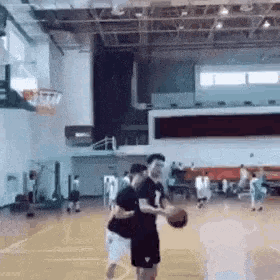 two men are playing basketball on a court in a gym .