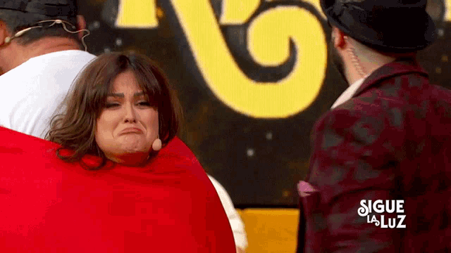 a woman is crying in front of a yellow sign that says sigue la luz