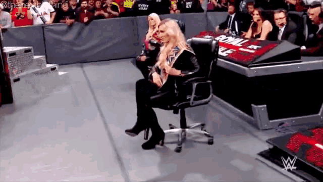 a woman is sitting in a chair in front of a wwe logo