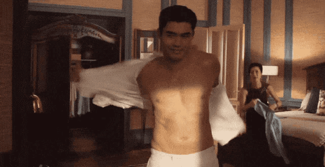 a shirtless man is standing in a room with a woman