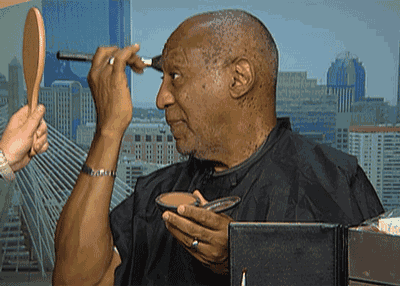 a man is applying makeup to his face while looking at himself in a mirror