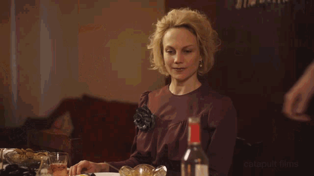 a man is pouring a drink into a glass while a woman looks on