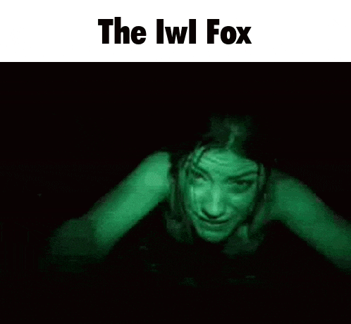 a woman is crawling in the dark with a green light coming out of her eyes .