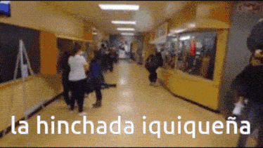 a blurred image of people walking in a hallway with the words la hinchada iquiquena