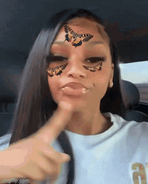 a woman in a car with butterflies on her face .