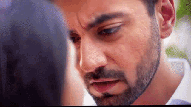 a close up of a man 's face with a beard looking at a woman .