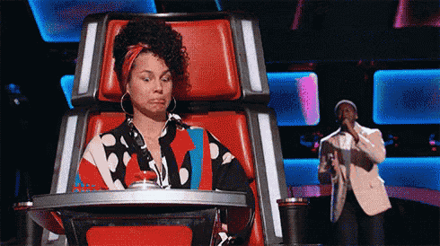 a woman is sitting in a red chair while a man is singing into a microphone .
