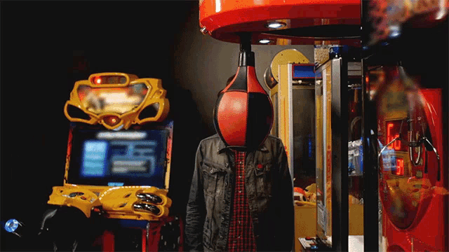 a man stands in front of a boxing machine with a red and black punching bag