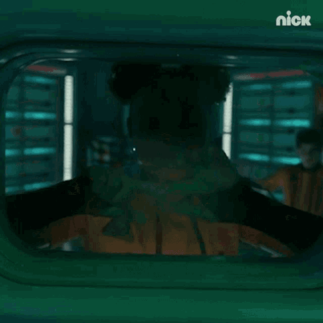 a person is looking out of a window with the nick logo on the bottom