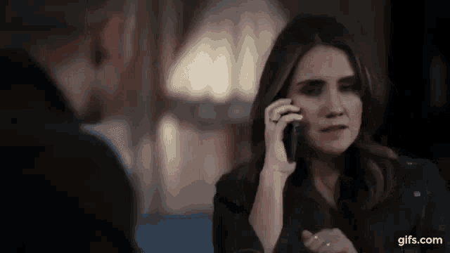 a woman is talking on a cell phone to a man while sitting at a table .