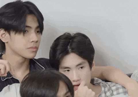 a group of young men are sitting next to each other and one of them is making a funny face .