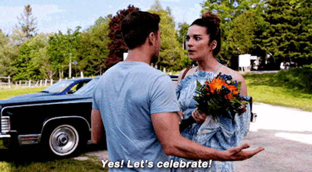 a man standing next to a woman holding a bouquet of flowers and saying " yes let 's celebrate "